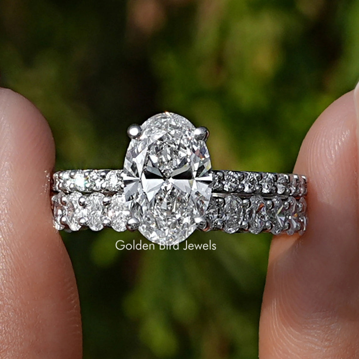 Oval Cut Lab Diamond Bridal Ring Set Held Between Fingers