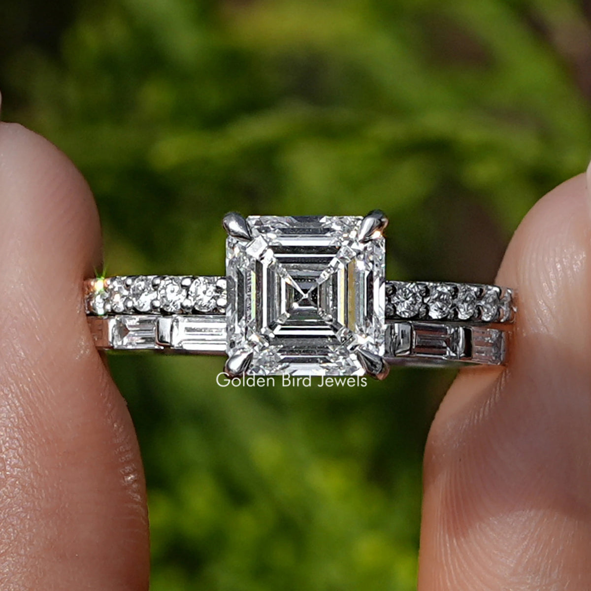 Square Emerald Lab Diamond Wedding Ring Set Held Between Fingers