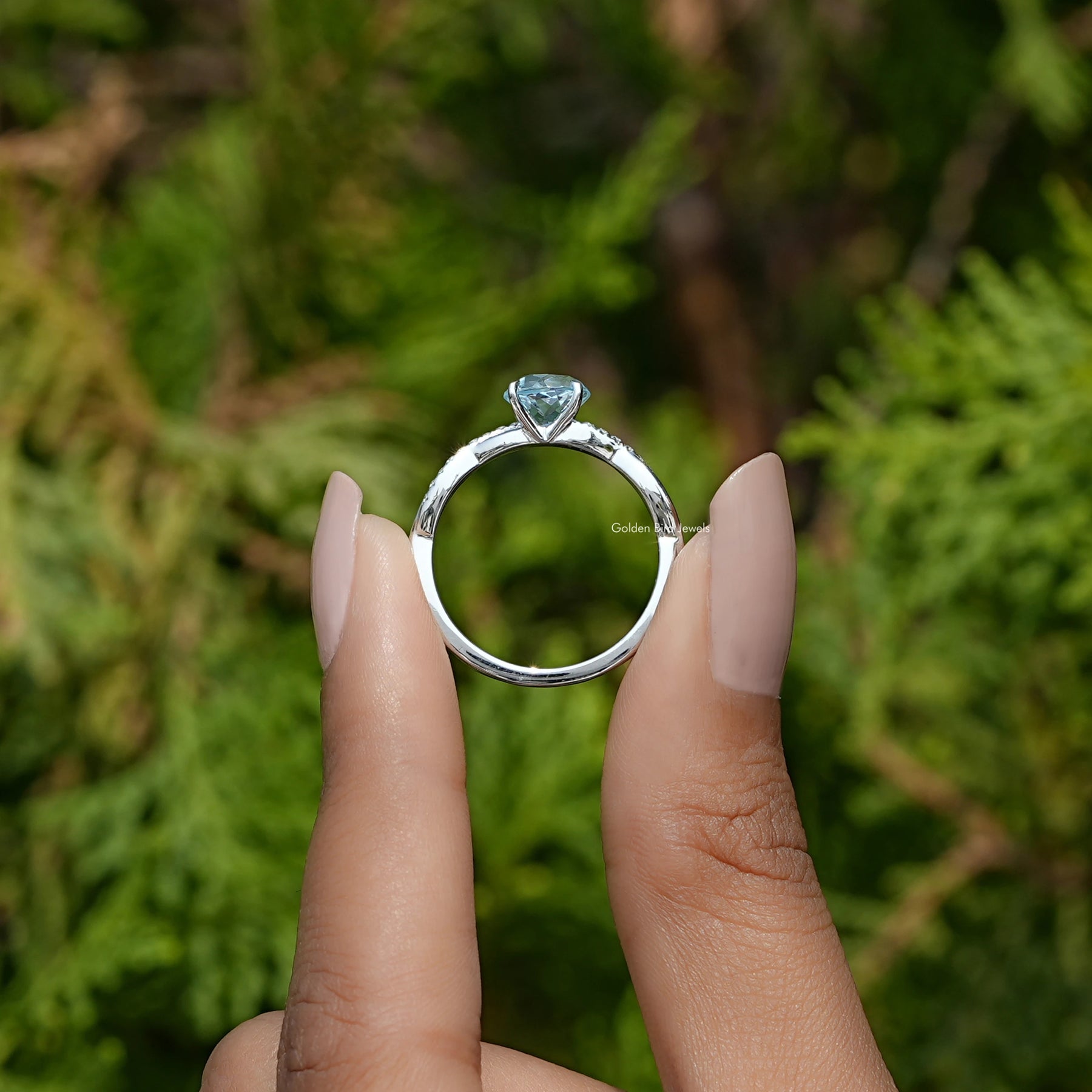 Back View of Aquamarine Round Cut Gemstone Engagement Ring In two fingers