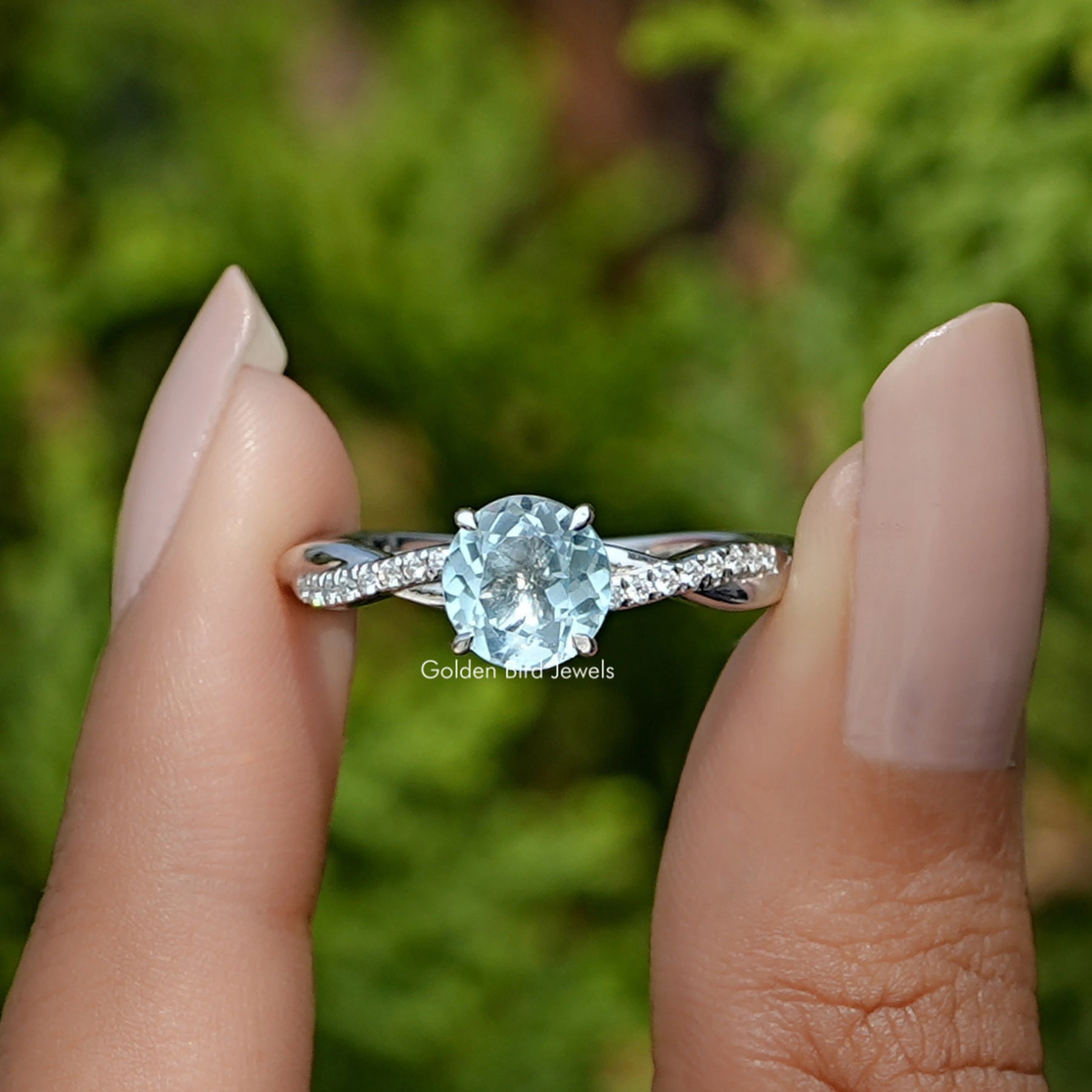 Front View of Aquamarine Round Cut Gemstone Ring In two Fingers