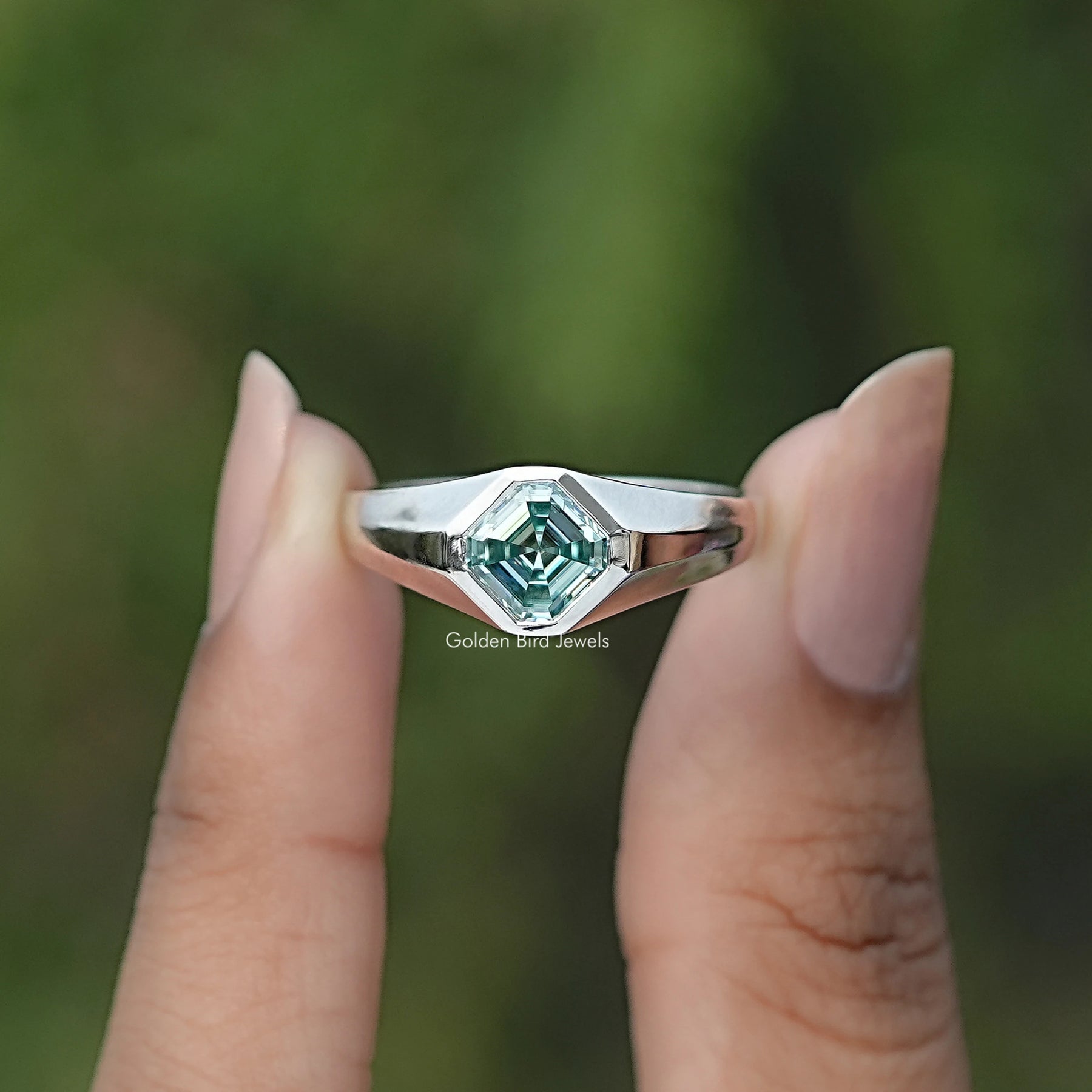 Front view of Blue Asscher Cut Moissanite Solitaire Ring in two fingers