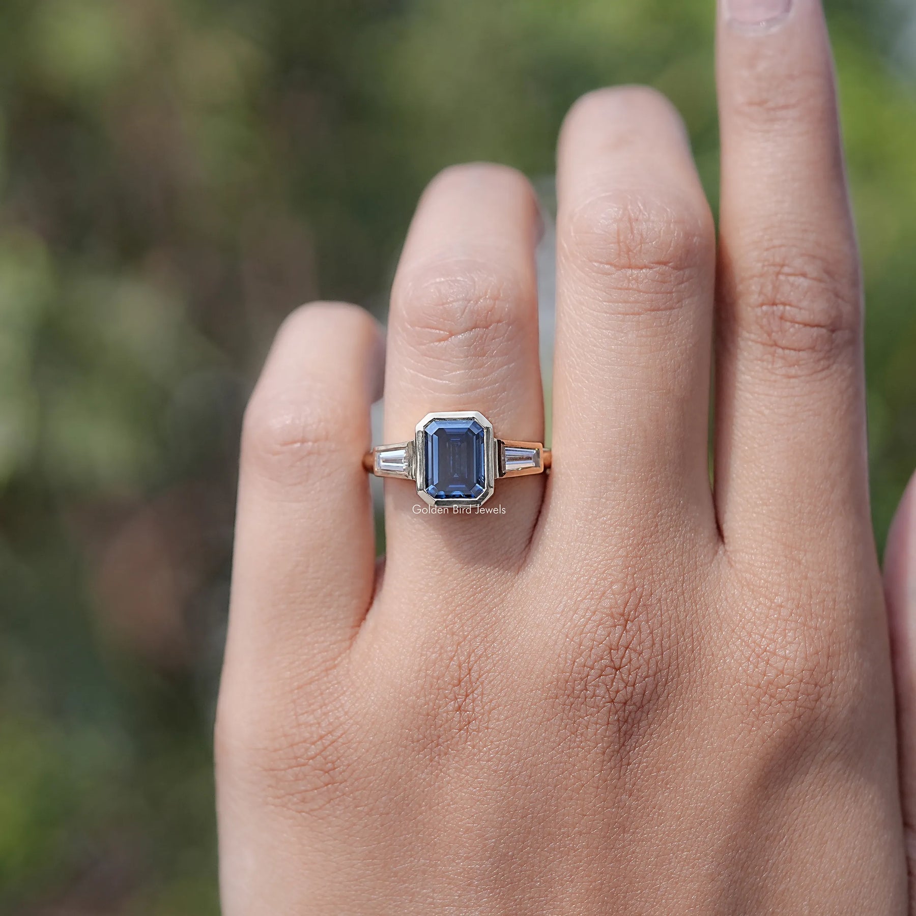 In finger view of Emerald Cut Moissanite Three Stone Engagement Ring