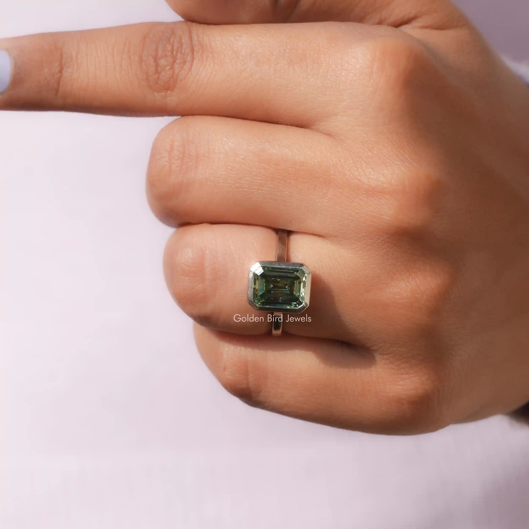 Clear View of Green Emerald Cut Solitare Ring In a finger