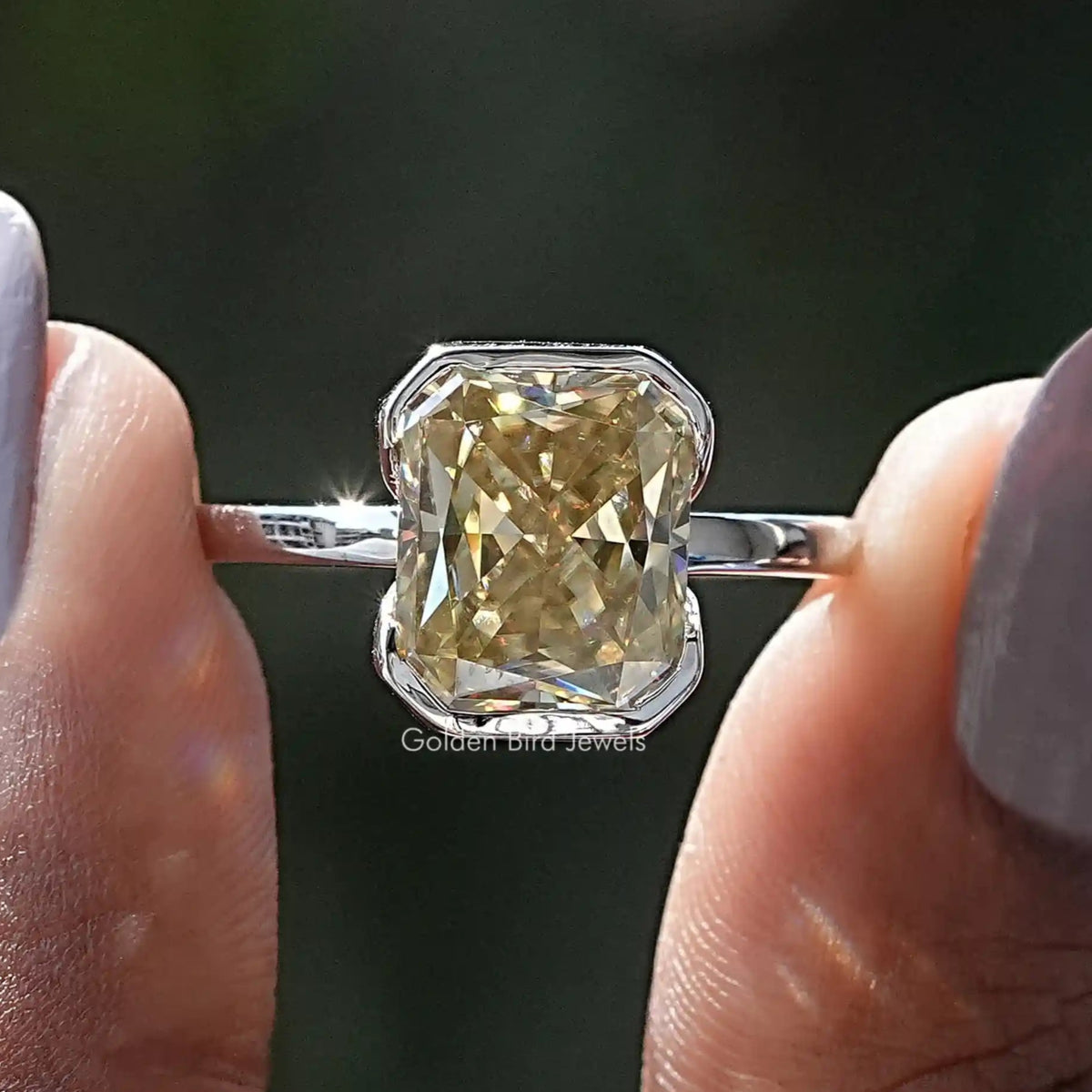Two fingers holding the Yellow Radiant Cut Moissanite Solitaire Ring