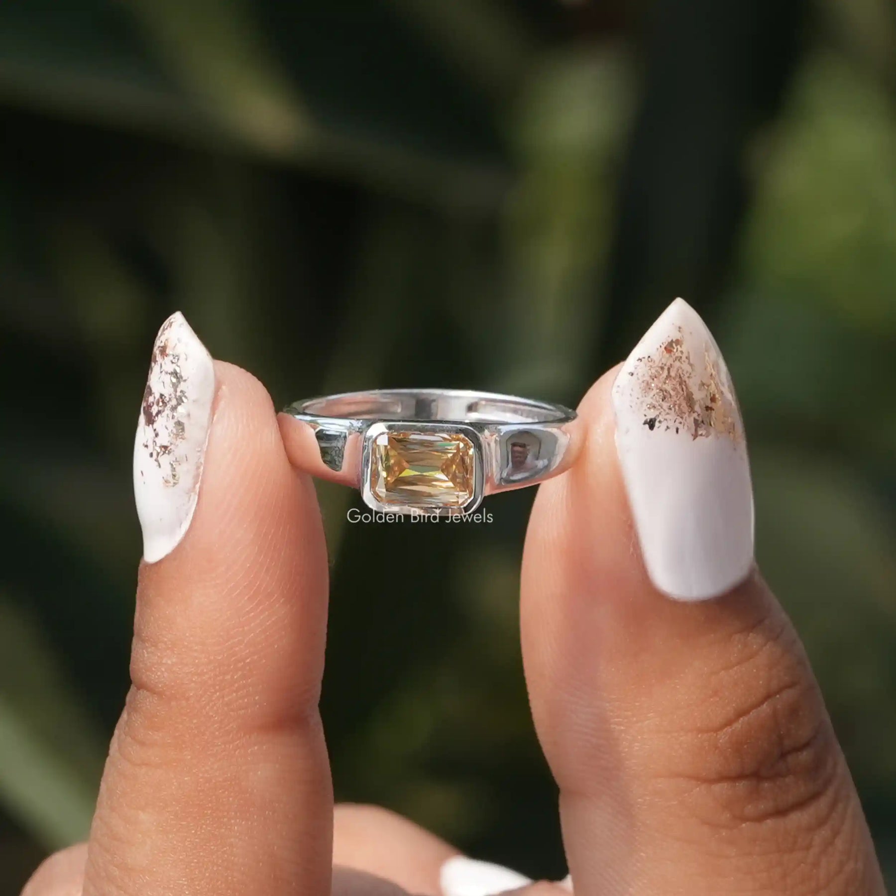 Two fingers holding the Champagne Criss Cut Moissanite Solitaire Ring