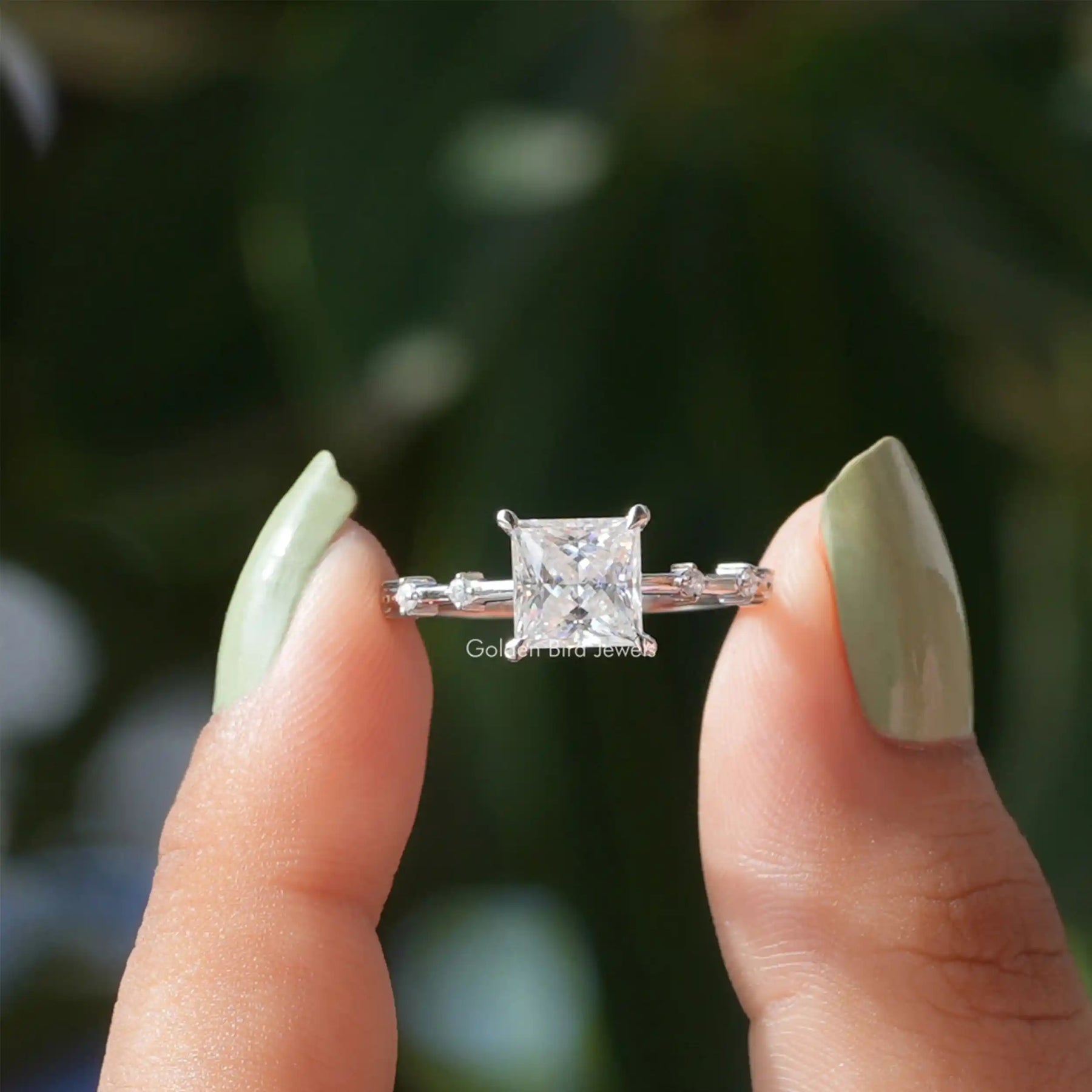 Two fingers holding the Princess Cut Moissanite Solitaire Ring