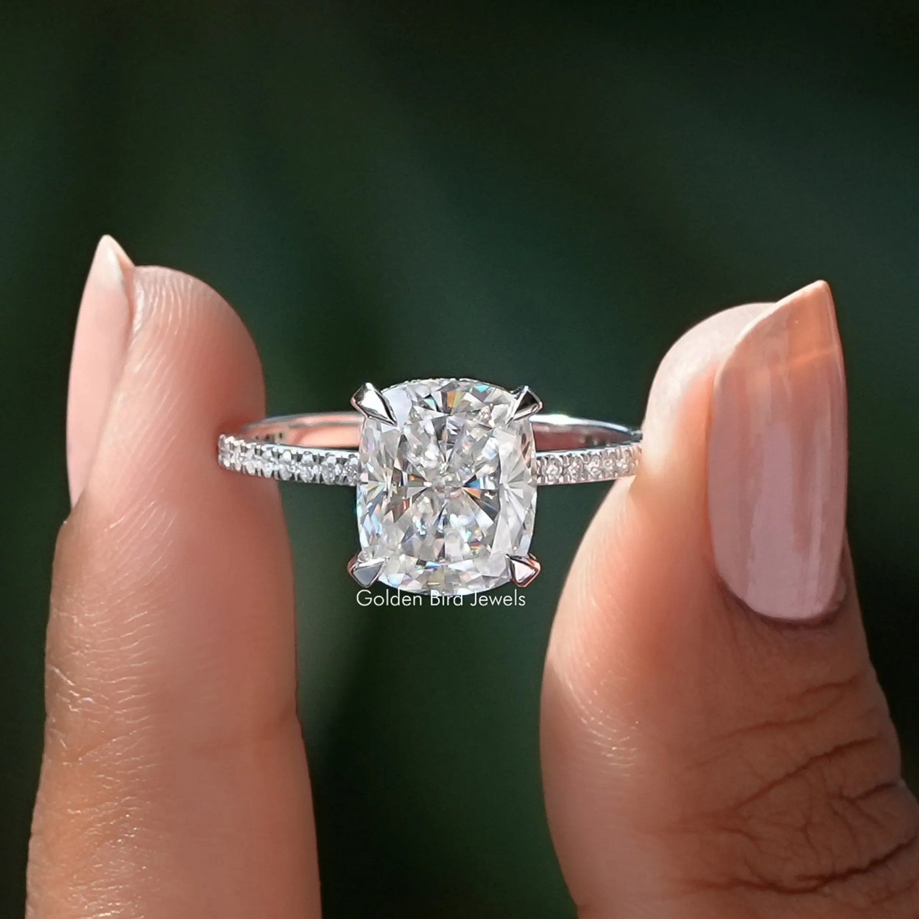 Two fingers holding the Crushed Ice Cushion Cut Moissanite Halo Ring
