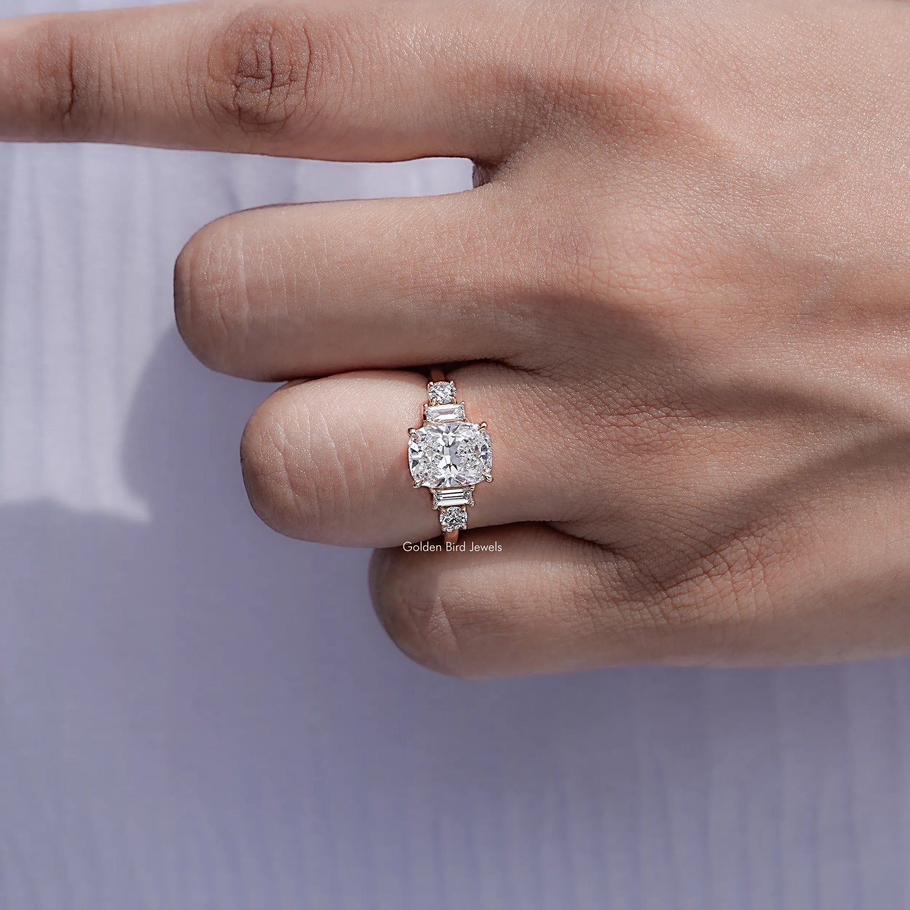 Detailed view of Cushion And Baguette Diamond Five Stone Ring Held in Finger