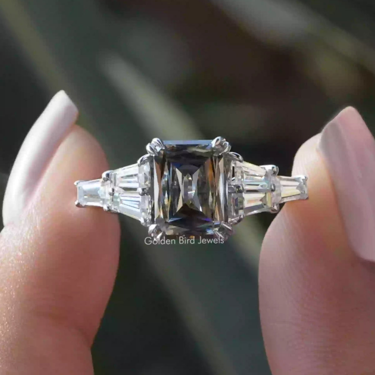Two fingers holding the Criss Cut Moissanite Engagement Ring