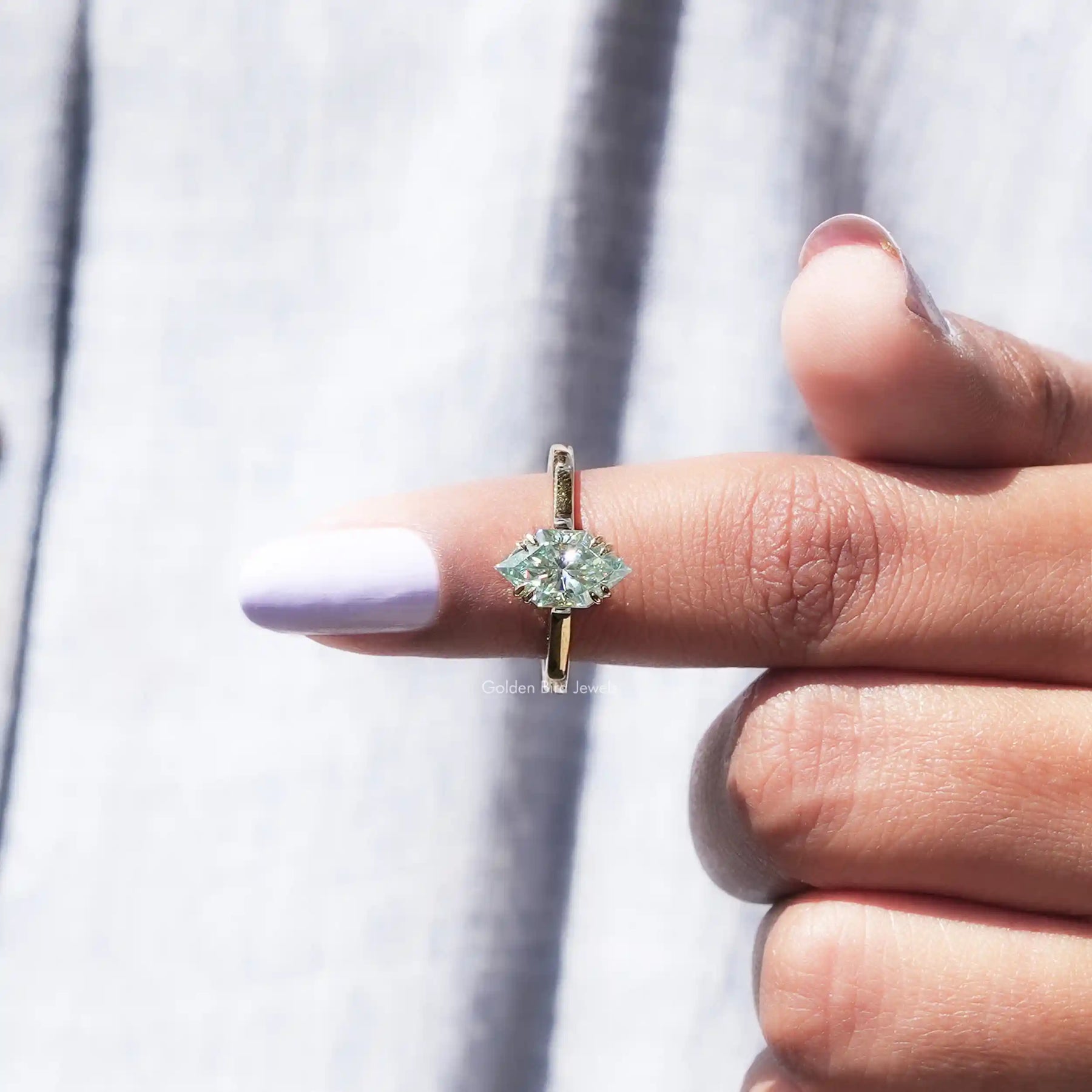 In finger front view of blue moissanite ring