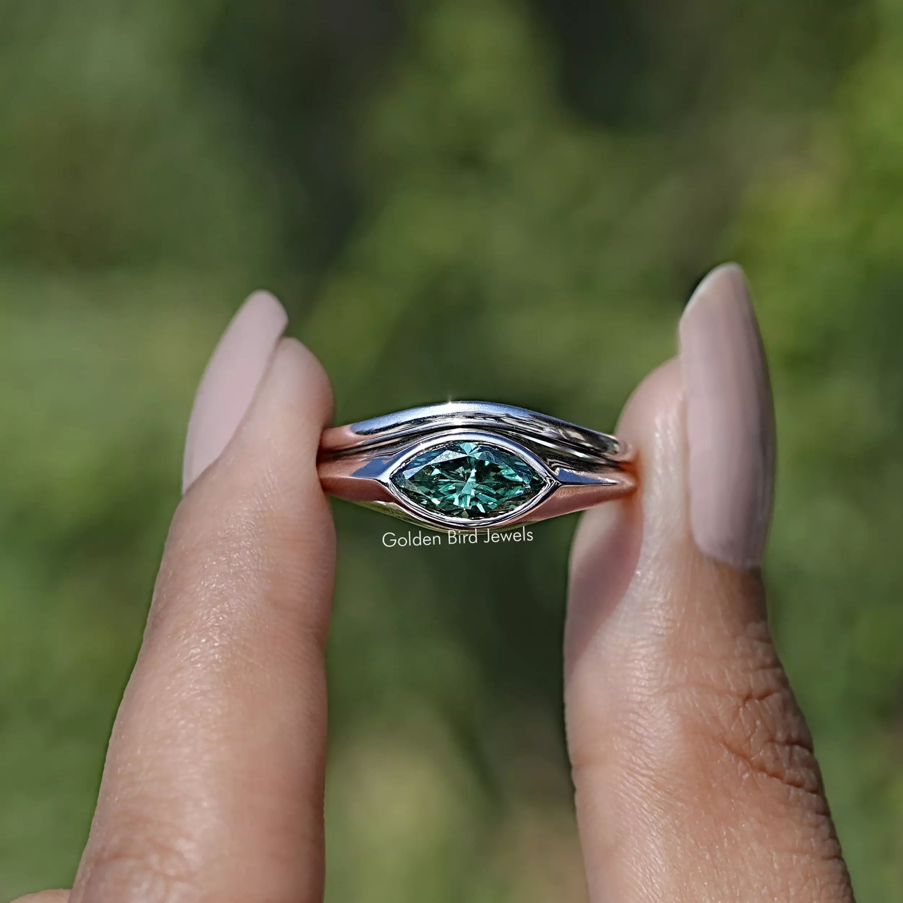 Front view of East West Green Marquise Bezel Set Moissanite Ring Set in two fingers