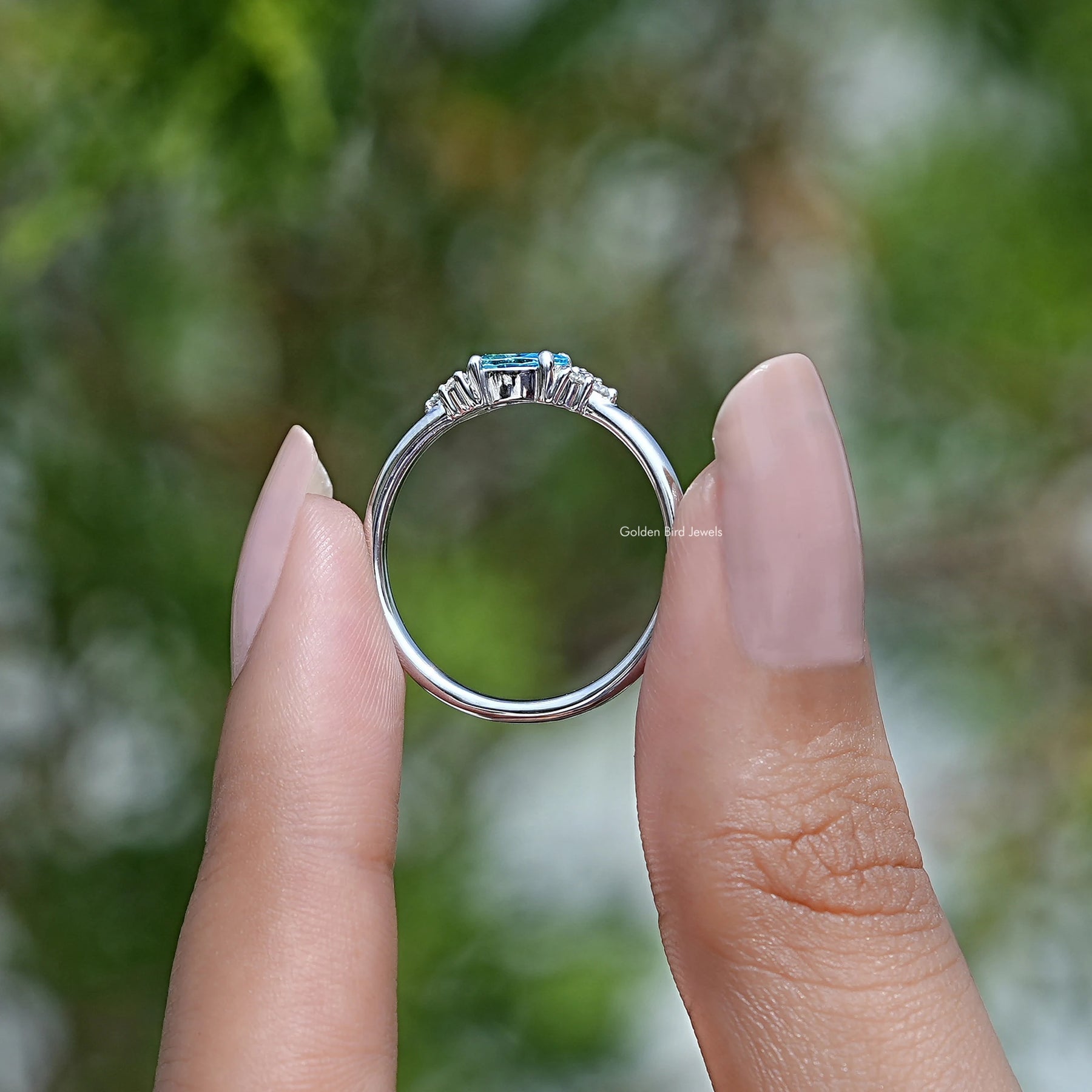 Back View of Emerald Cut Gemstone Engagement Ring In two fingers