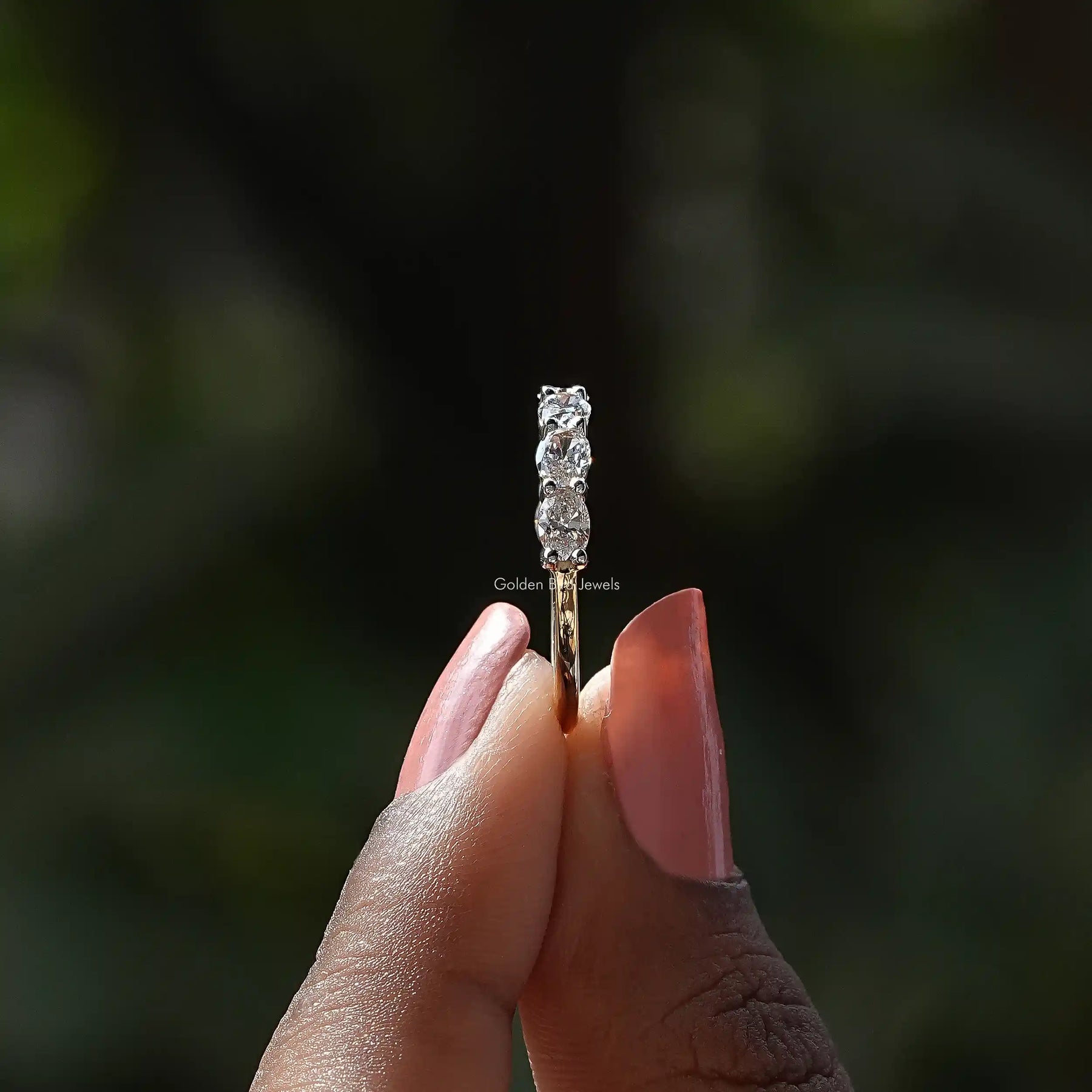 Side View of Oval Cut Lab Diamond Eternity Wedding Band In two fingers