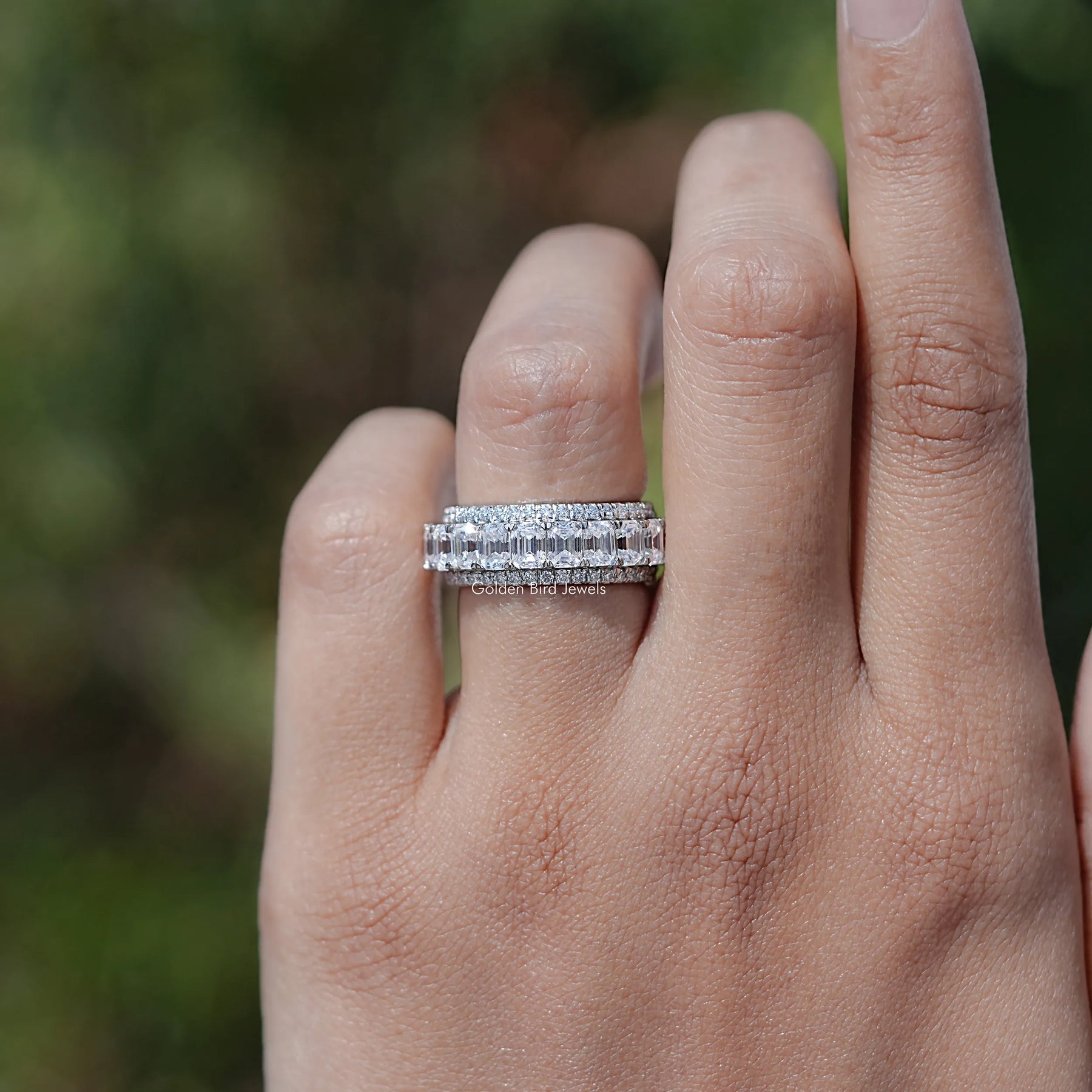 In finger front view of Emerald and Round Cut moissanite three row band
