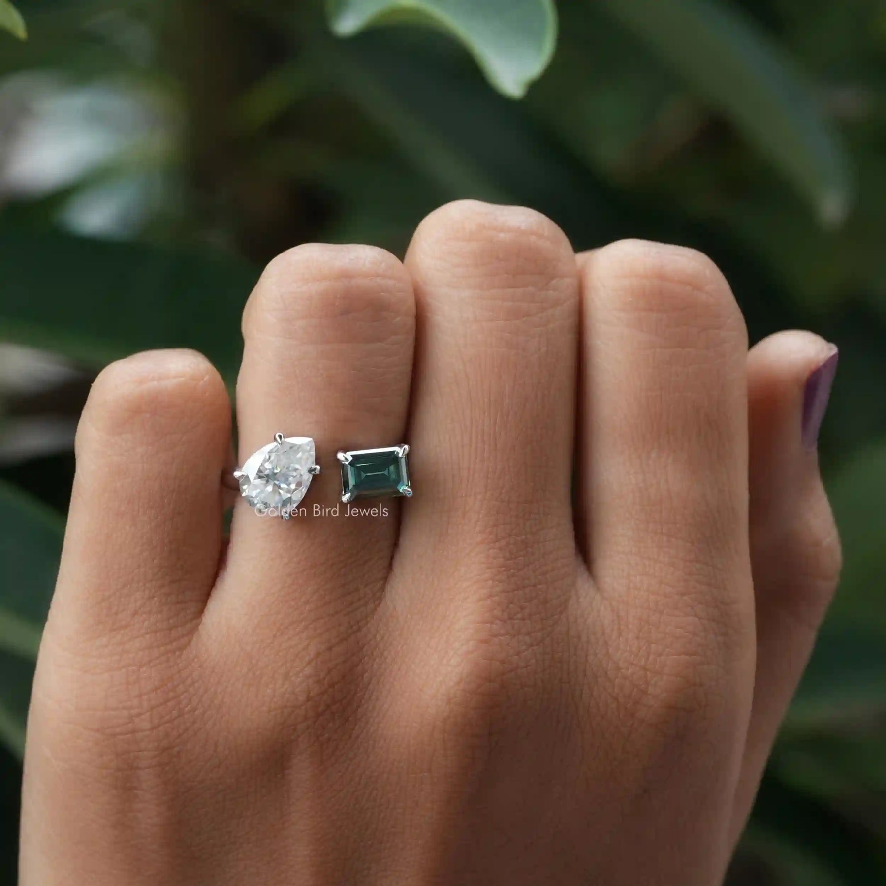 Emerald and pear-cut moissanite ring in a secure setting