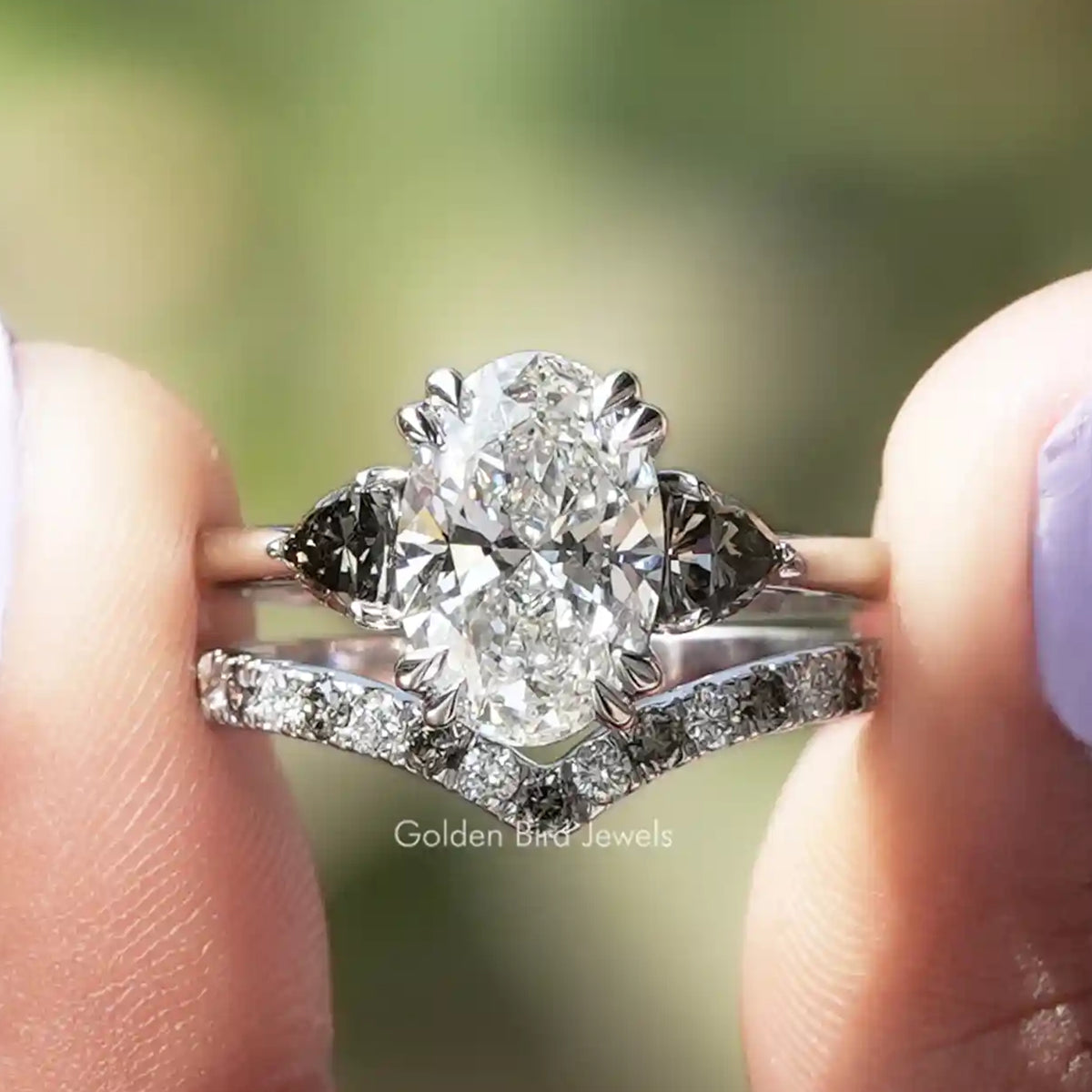 Oval Cut Lab Grown Diamond Bridal Set Ring Held Between Fingers