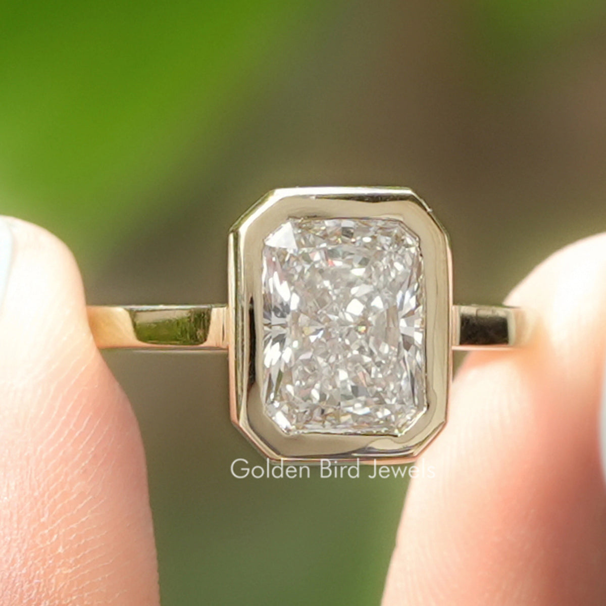Radiant Cut Lab Diamond Bezel Set Solitaire Ring Held Between Fingers