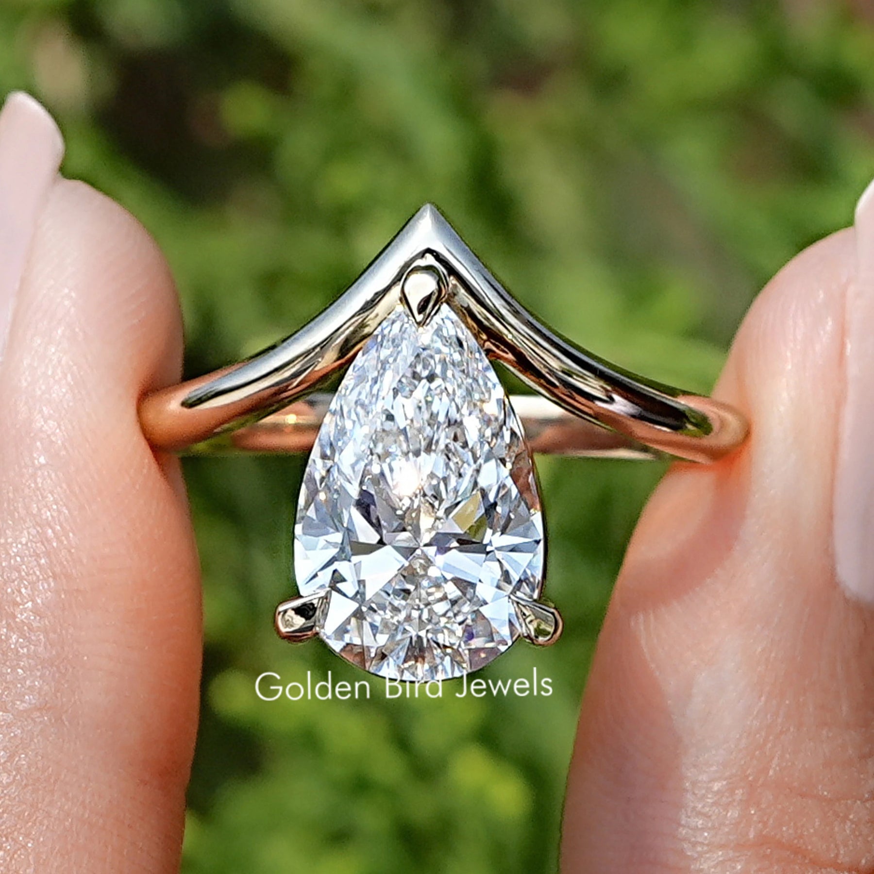 Pear Cut Lab Diamond V Shaped Curved Solitaire Ring Held Between Fingers