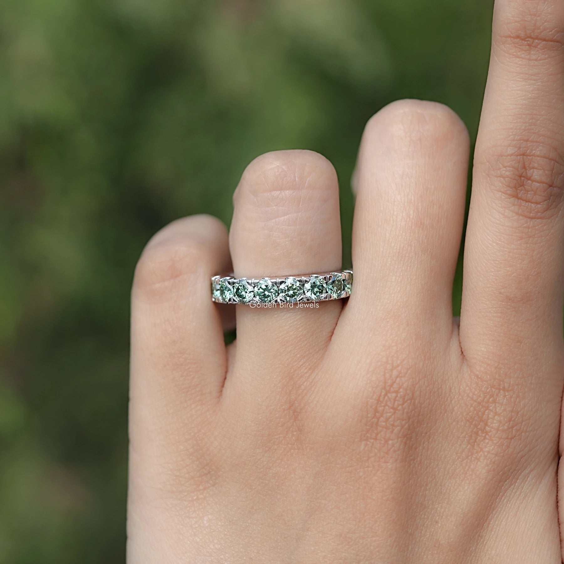 In finger front view of Green Round Cut Moissanite Eternity Band