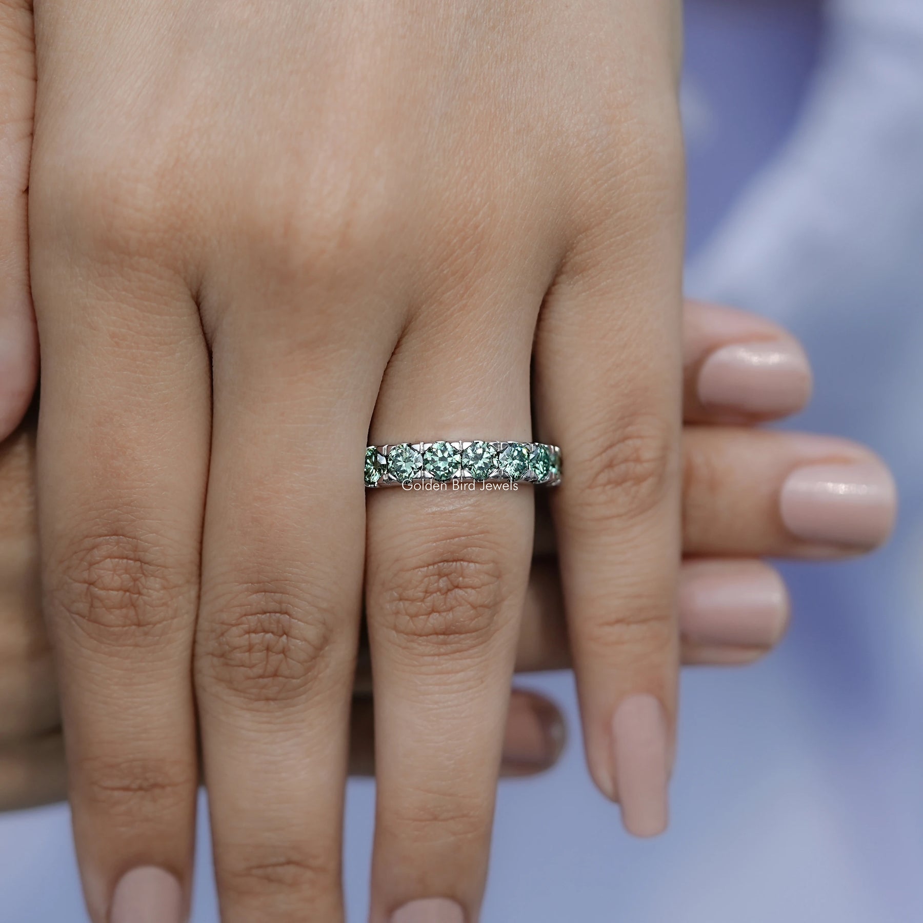 In finger front view of Green Round Cut Moissanite Eternity Band Min unique shape