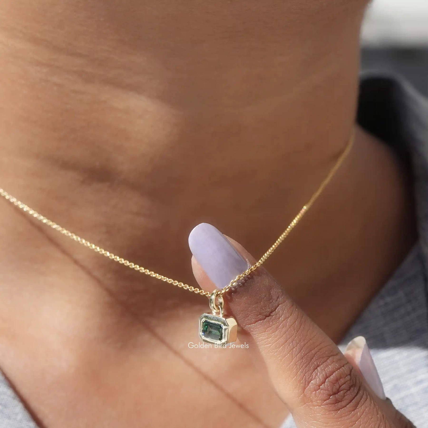 Side view of green emerald pendant In yellow Gold