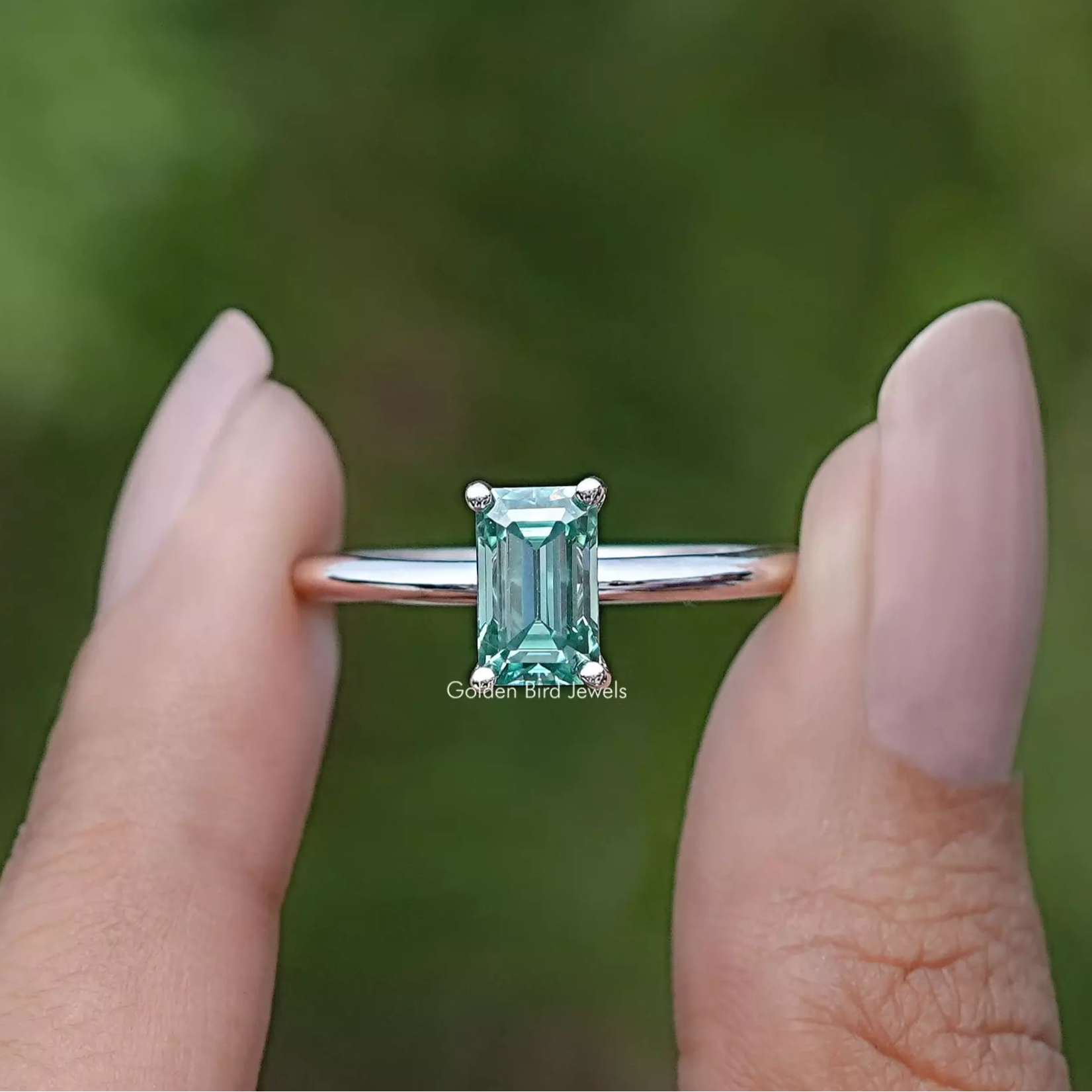 Front view of Green Emerald Cut ring holding in two fingers