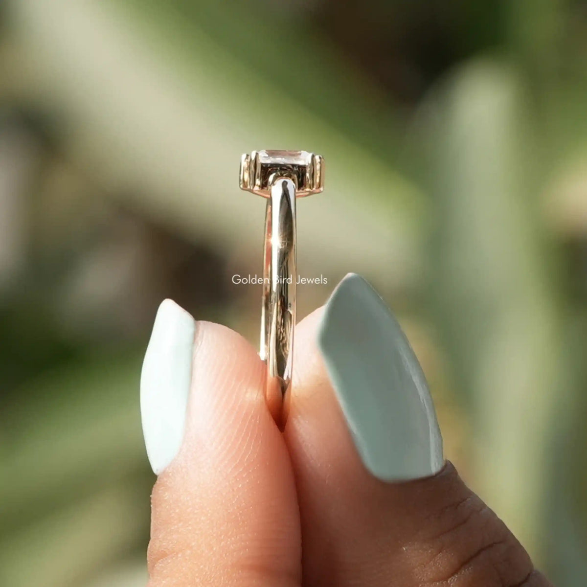 Side view of moissanite ring holding on two fingers