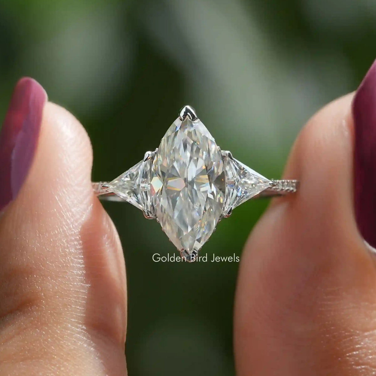 Two fingers holding the Marquise And Triangle Cut Hidden Halo Ring