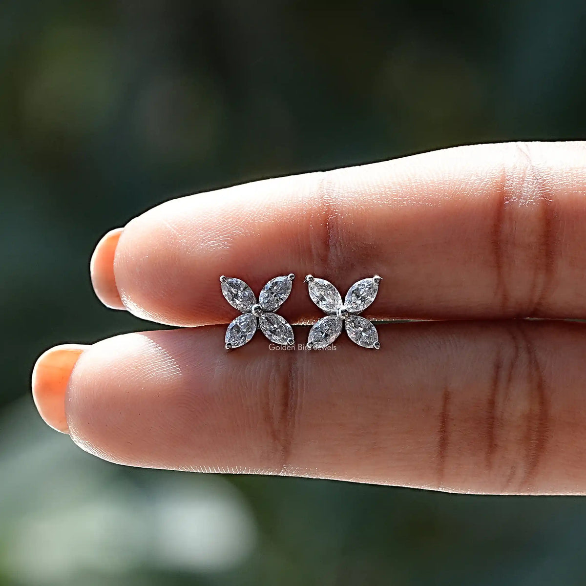 Diamond studs earing in holding on  center of fingers