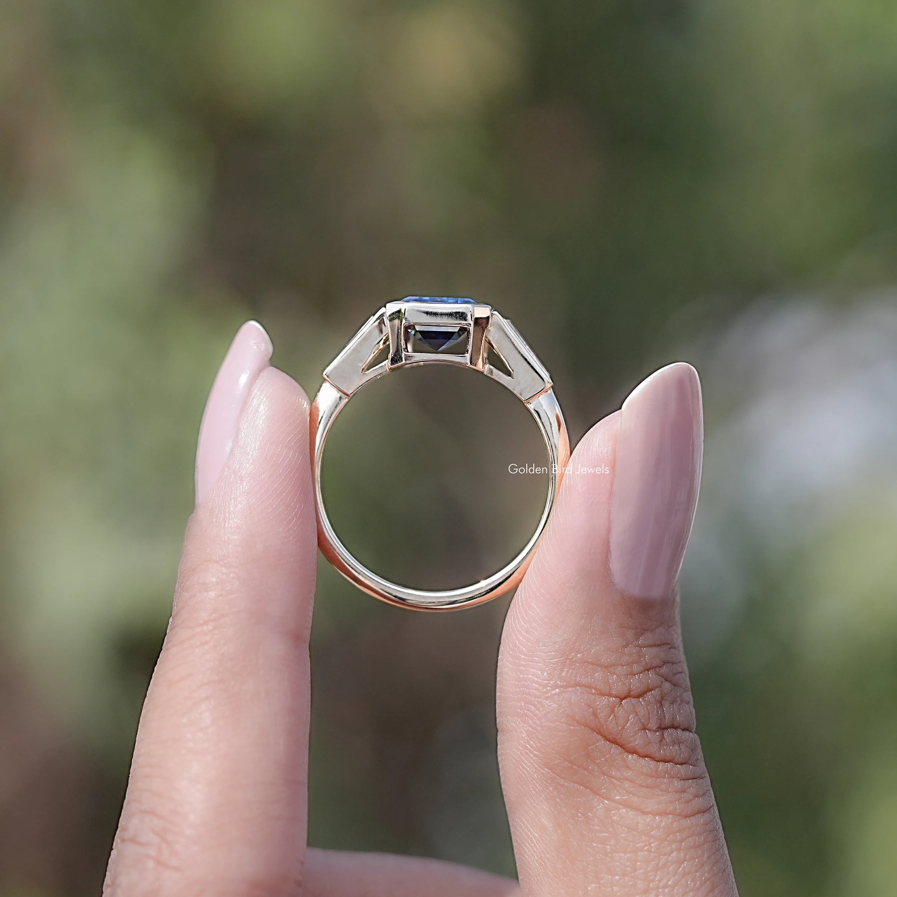 Back view of Emerald Cut Moissanite Three Stone Engagement Ring in secure setting
