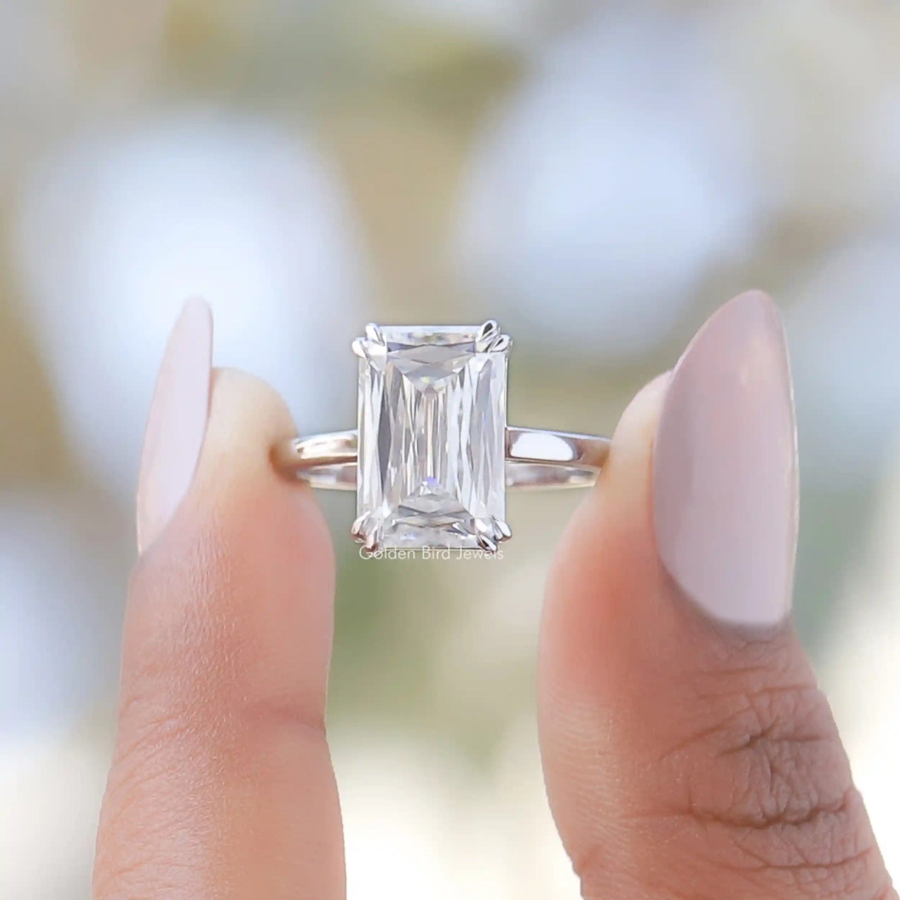 Two fingers holding the Criss Cut Moissanite Solitaire Ring