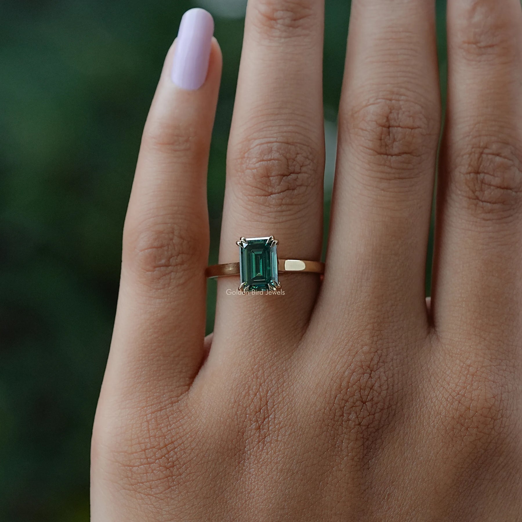In finger view of halo emerald moissanite ring