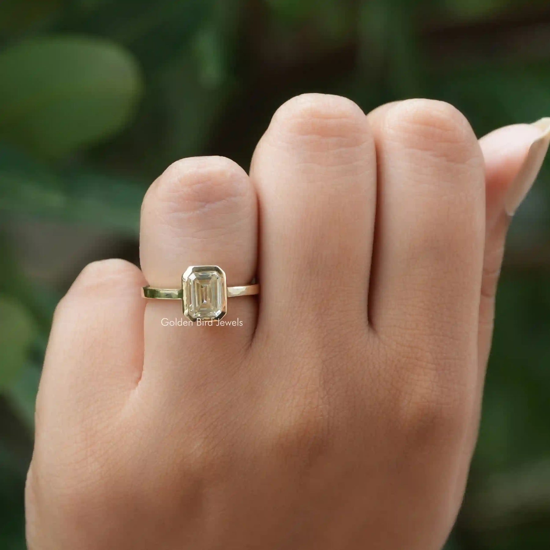 Close-up shot of emerald cut solitaire moissanite ring with sparkle.