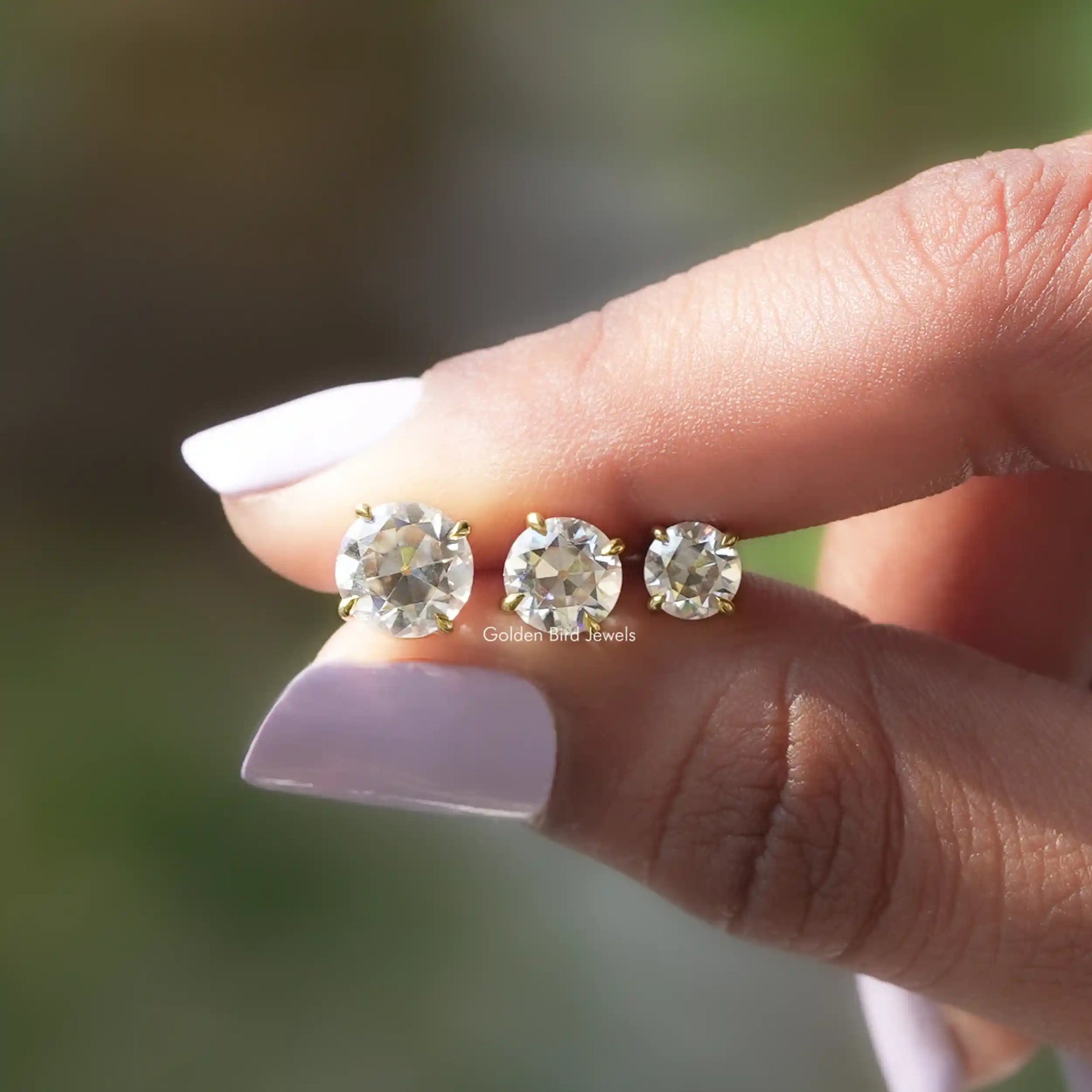 Different carat moissanite earrings holding in two fingers