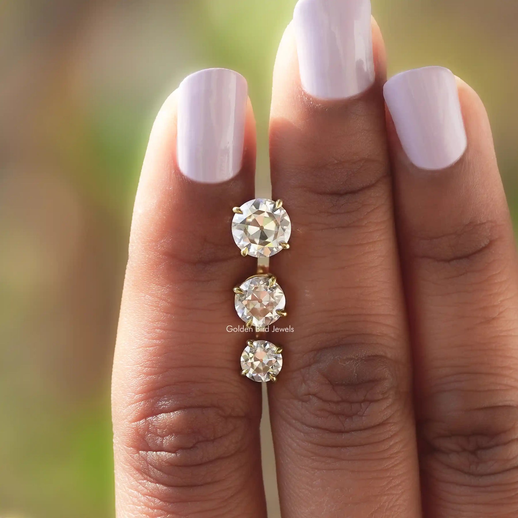 Close view of Colorless round-cut studs between two fingers