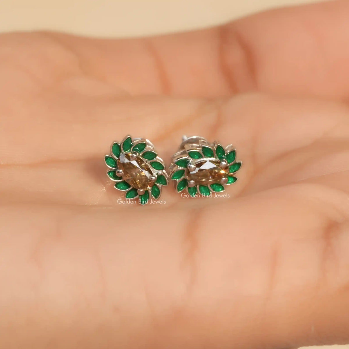 In hand view of oval shape halo stud earrings