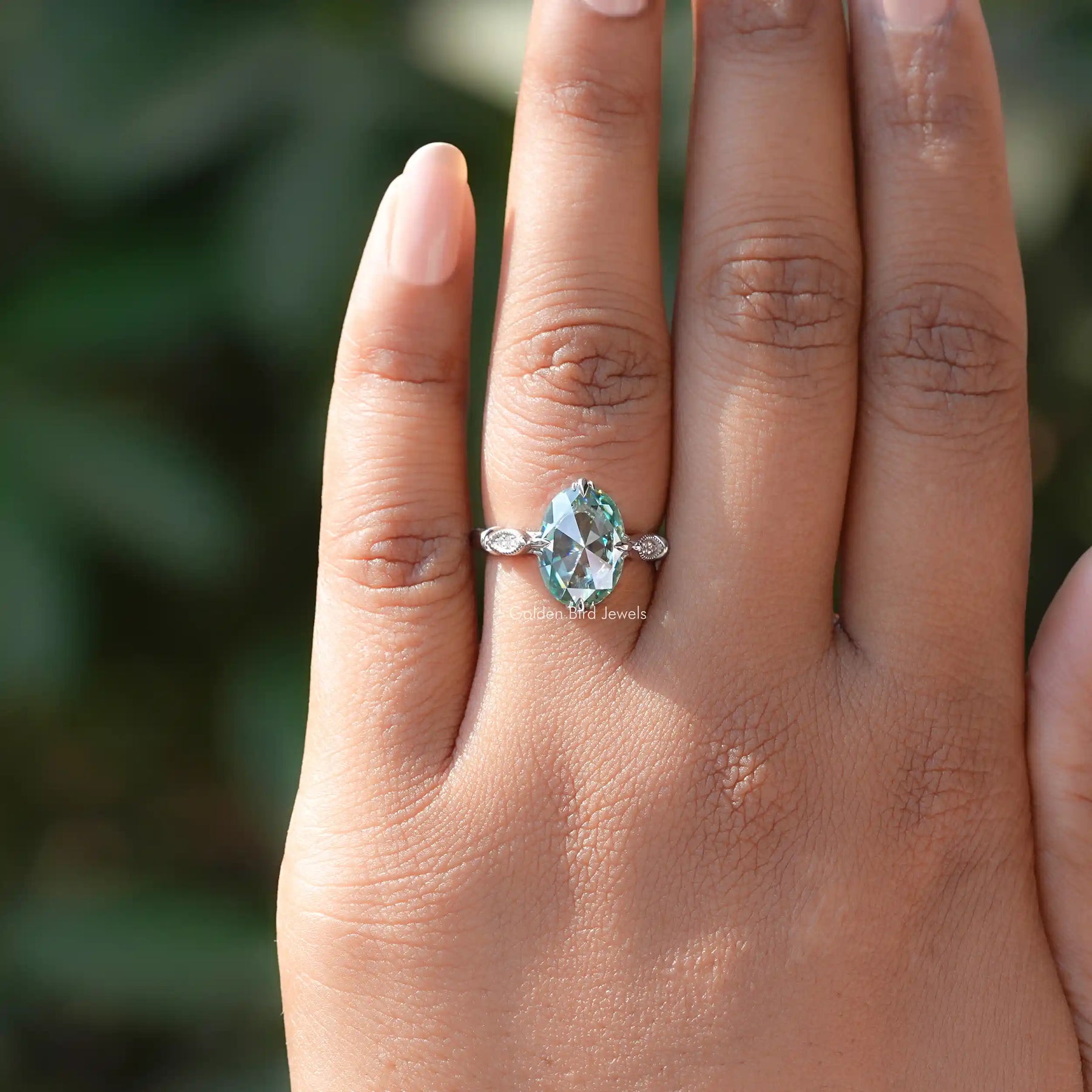 Stunning rose oval moissanite ring on a hand with side accents.