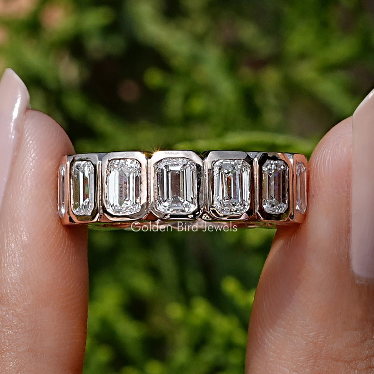 Emerald Cut Lab Diamond Bezel Set Eternity Band Held Between Finger