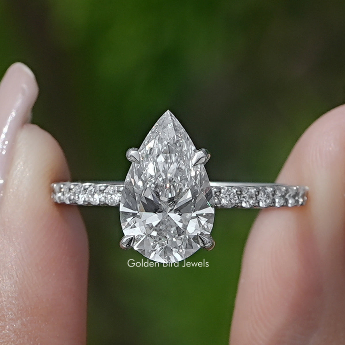 Pear Cut Diamond Solitaire Ring Held Between Fingers