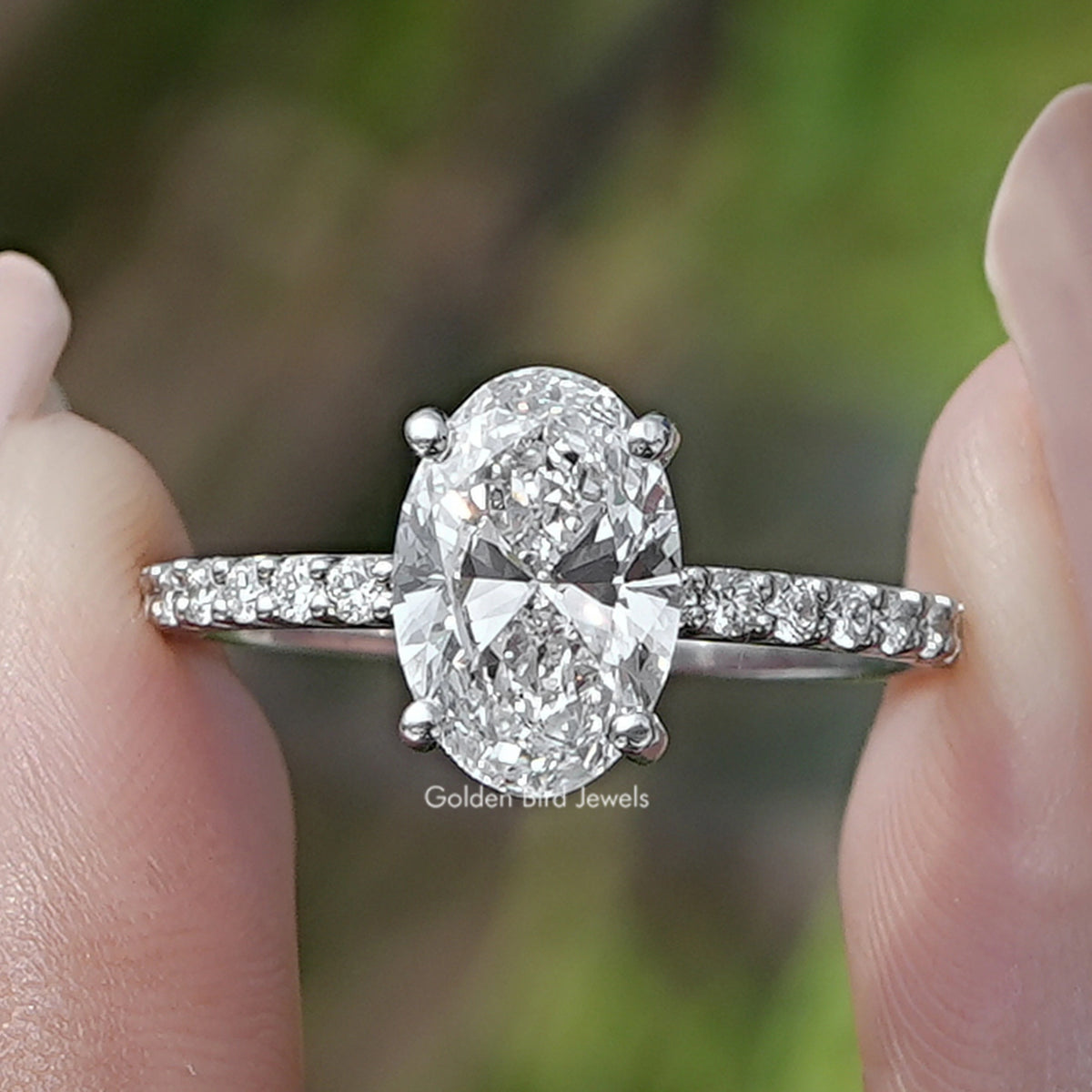 Oval Cut Diamond Solitaire Ring Held Between Fingers