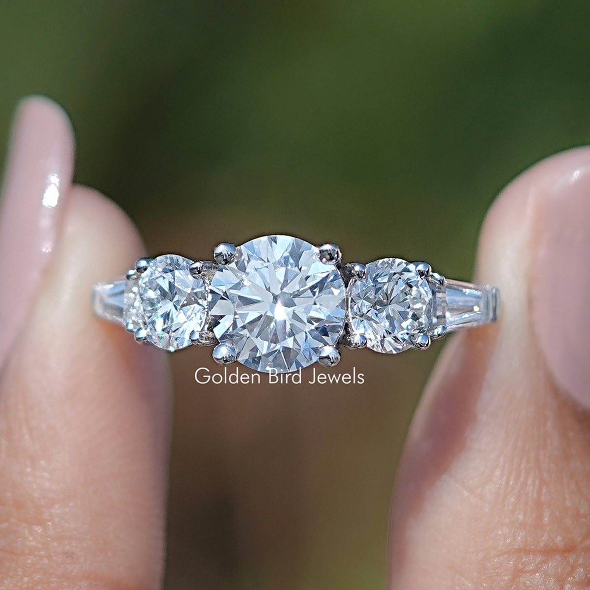 Round And Tapered Baguette Cut Five Stone Ring Held Between Fingers