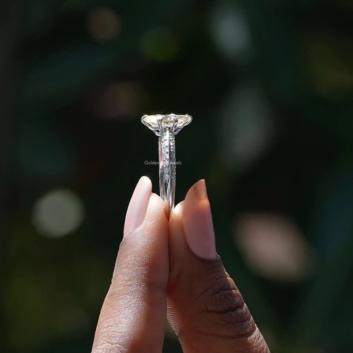 Side View of Moval Cut Moissanite Accent Ring In two fingers