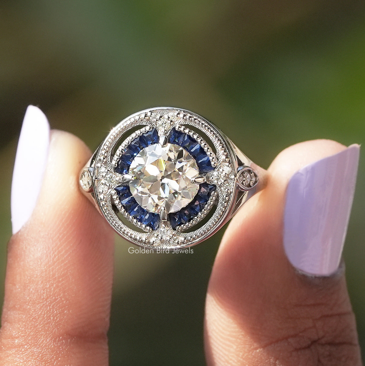 Two fingers holding the Old European Round Cut Moissanite Ring