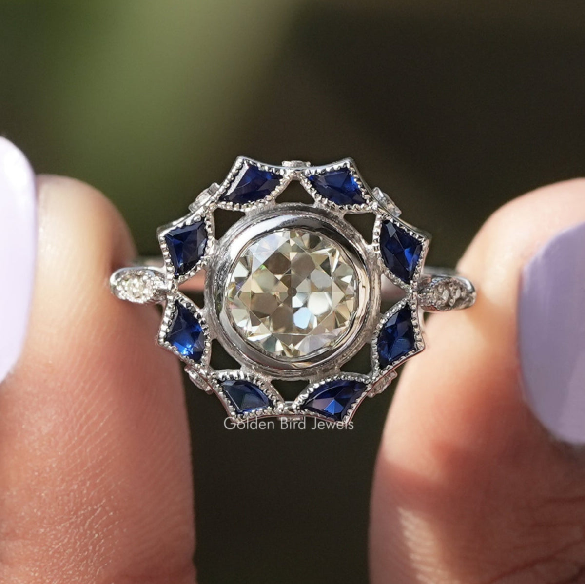 Two fingers holding the Old European Round Cut Bezel Set Moissanite Ring