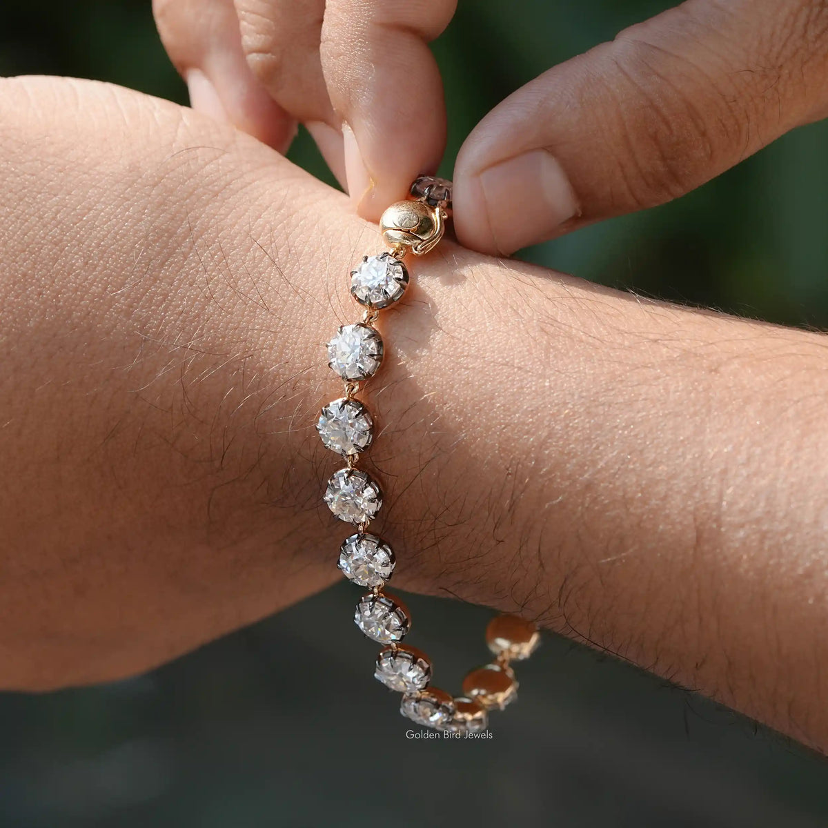 In Finger holding view of round cut moissanite tennis bracelet