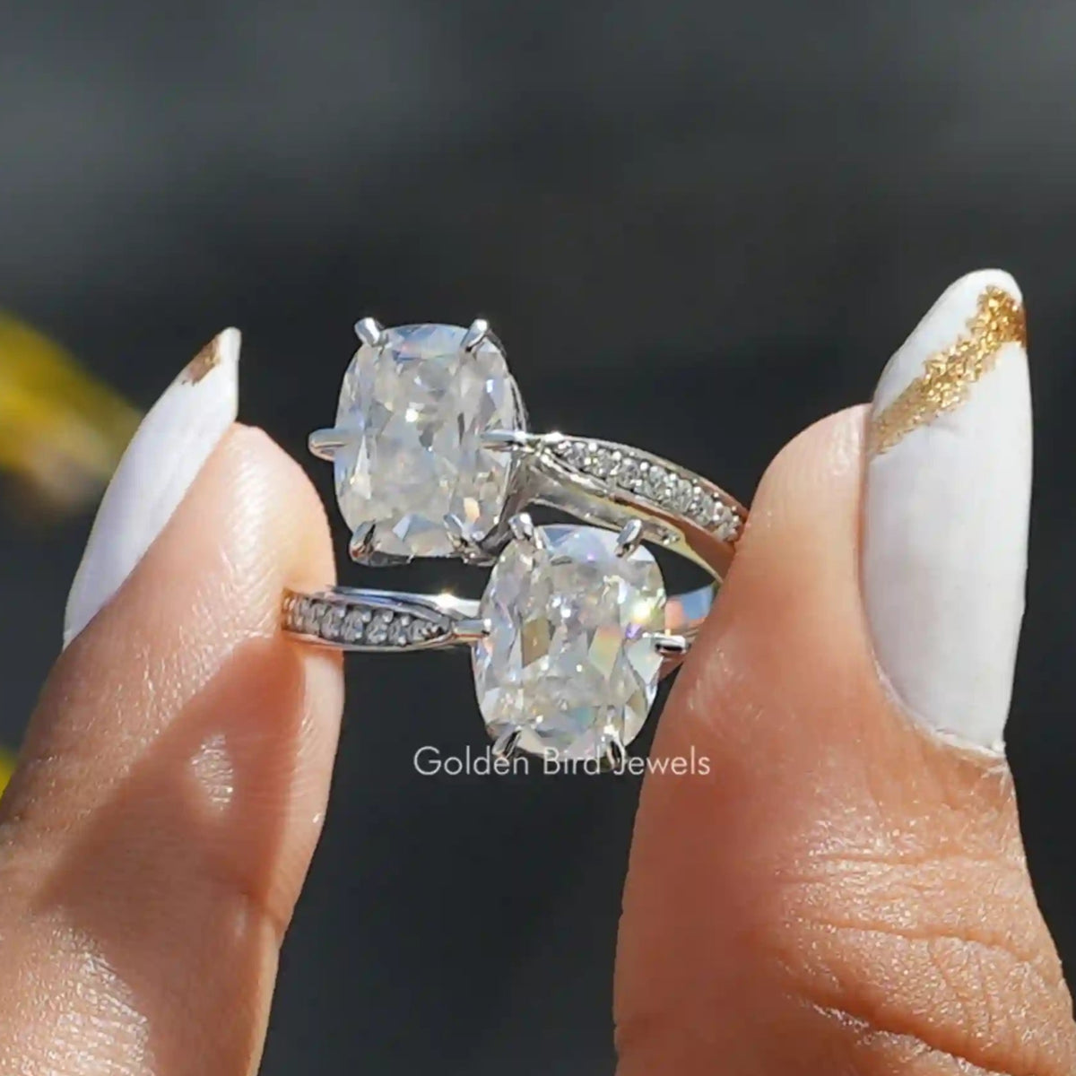 Two fingers holding the Old Mine Cushion Cut Moissanite Ring