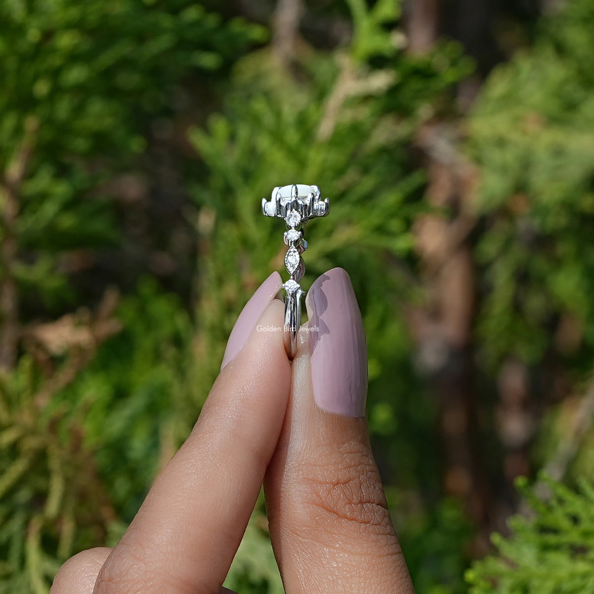 Side View of Round Cut Gemstone Accent Ring In two fingers