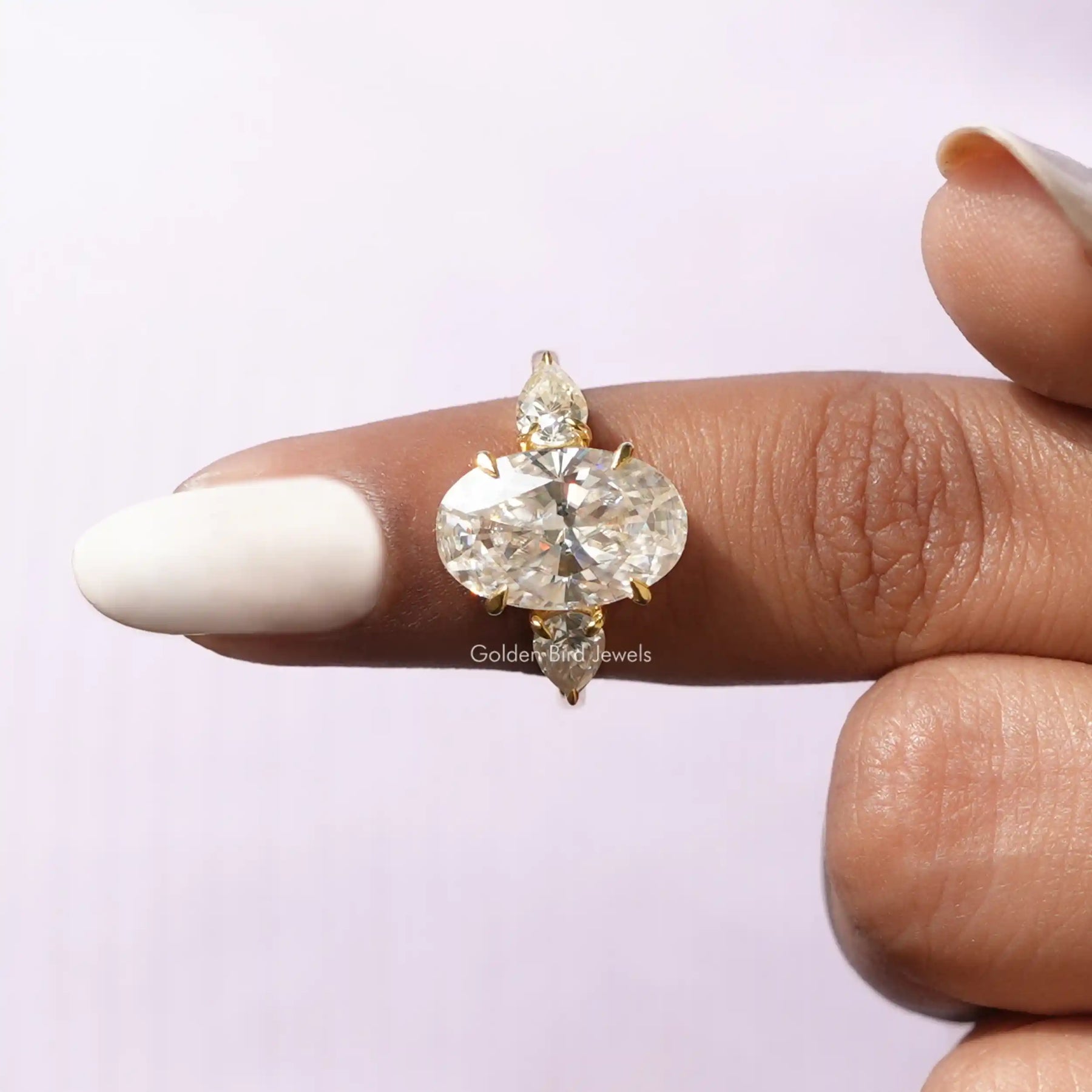 In finger front View of Oval And Pear Moissanite Three Stone Ring