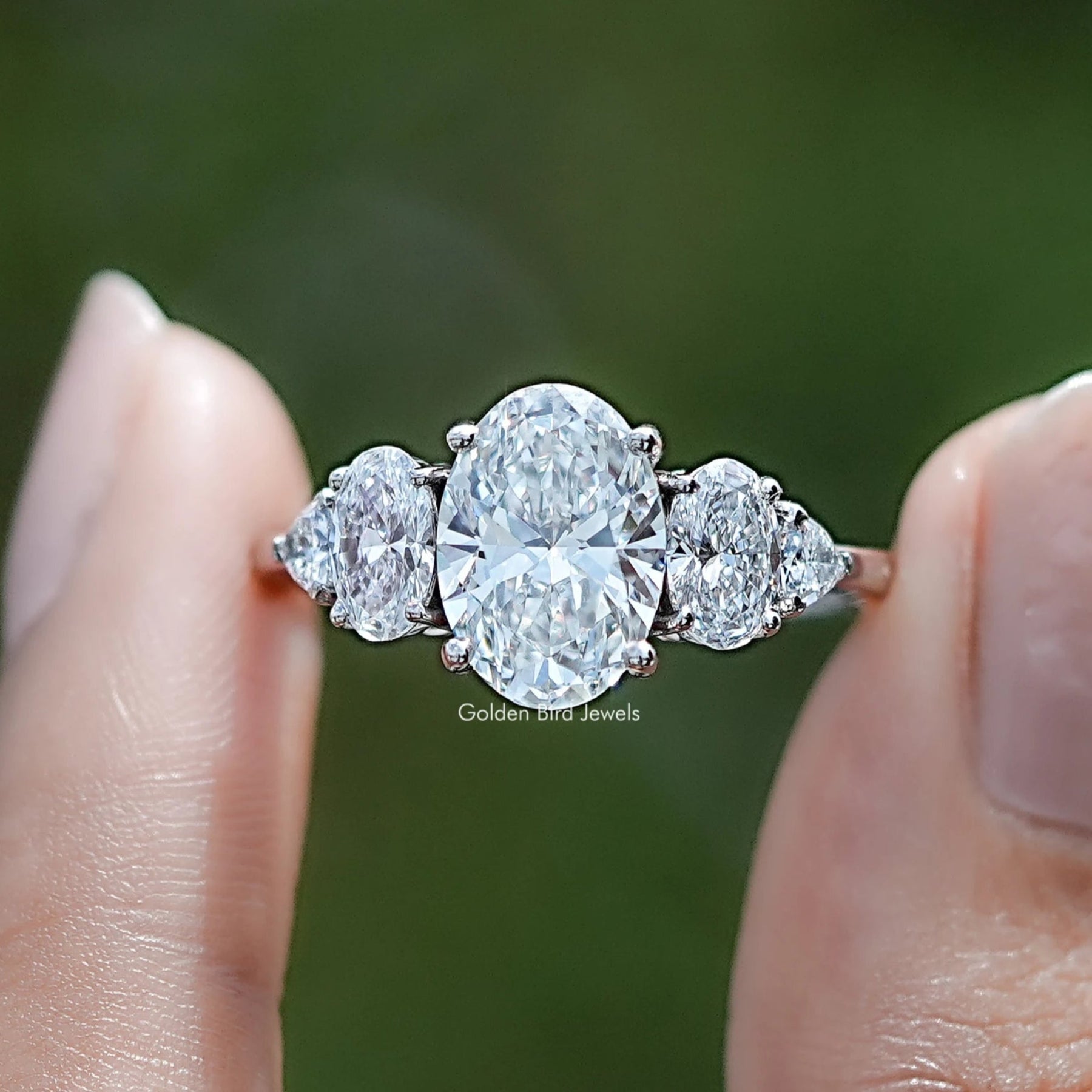 Oval And Trillion Lab Diamond Five Stone Ring Between Two Fingers