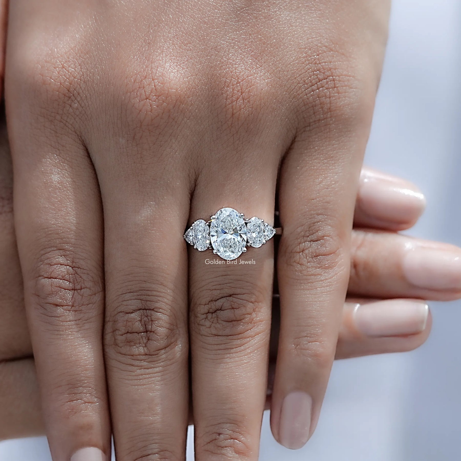 Top view of Oval And Trillion Diamond Five Stone Ring Held in Finger